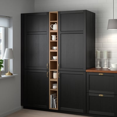 Schwarzer VADHHOLMA Schrank mit offener Tür, in dem Keramik und Bücher in der Nähe eines Fensters ausgestellt sind.