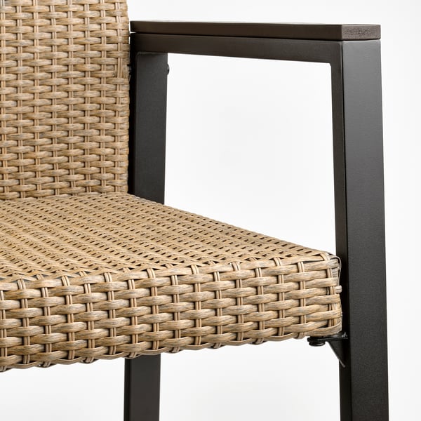 Nahaufnahme eines geflochtenen Outdoor-Stuhls mit geflochtenem Sitz und Rückenlehne, stabilem schwarzem Metallrahmen.