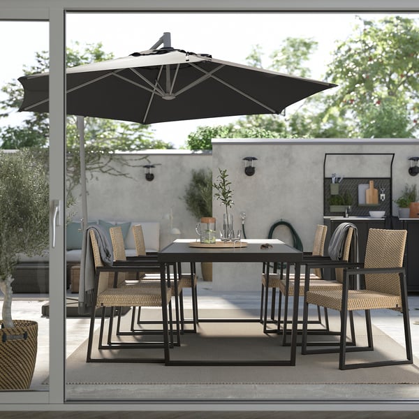 Moderne Terrasse mit schwarzer VÄRMANSÖ-Essgarnitur und Sonnenschirm. Sitze im Rattanstil, pulverbeschichteter Stahl, grauer Teppich.