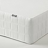 Das Bild zeigt eine Ecke einer weißen Ikea-Matratze, die den gesteppten Bezug und die verstärkte Kante hervorhebt.