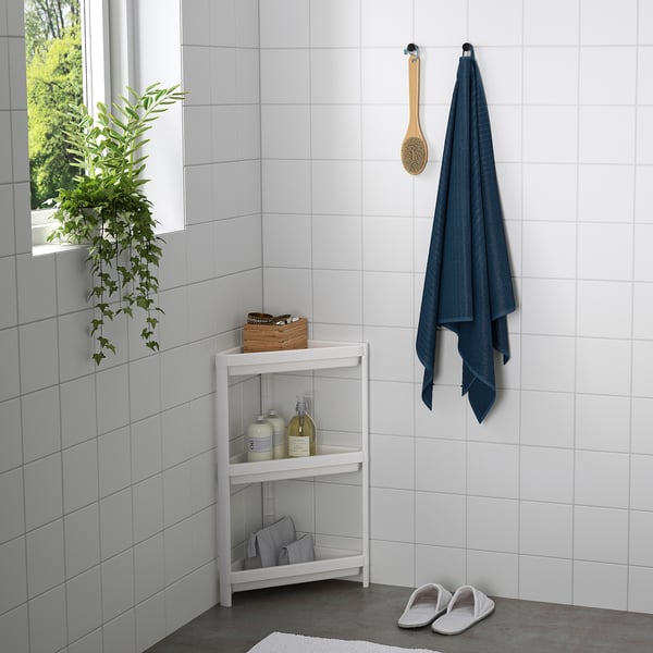 Kleines Badezimmerregal VESKEN mit Toilettenartikeln, Hängetuch und Hausschuhen; Passt in enge Räume, hält Gegenstände organisiert.