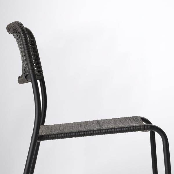Schwarzes geflochtenes Seitenprofil des Stuhls. Geschwungene Rückenlehne und Sitz mit Metallrahmen. Modernes Design, langlebig, stapelbar.