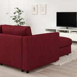 Modernes L-förmiges Sofa aus rotem Stoff in der Nähe eines Flachbildfernsehers, dessen Größe einem großen Teppich ähnelt.