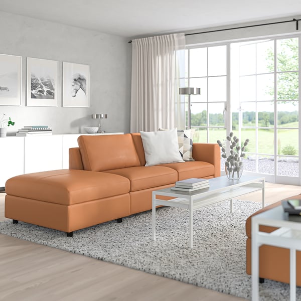 VIMLE orangefarbenes L-Sofa, klare Linien, weiche Kissen, weißer Couchtisch, natürliches Licht.