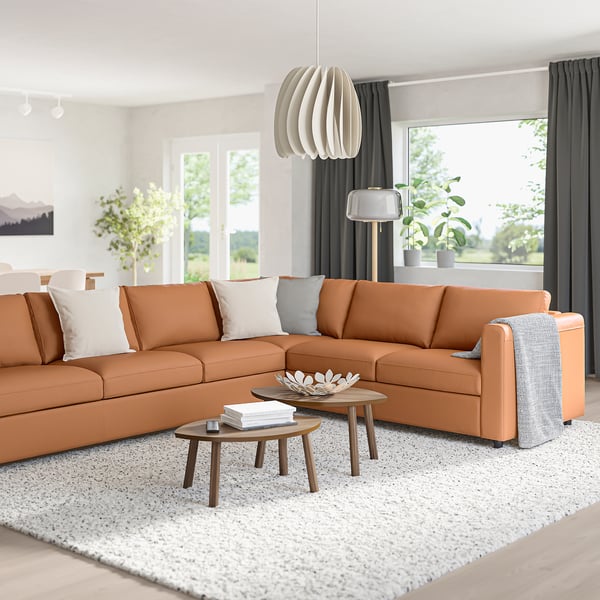 Modernes Wohnzimmer mit orangefarbenem VIMLE-Sofa, Couchtischen und großem Fenster.