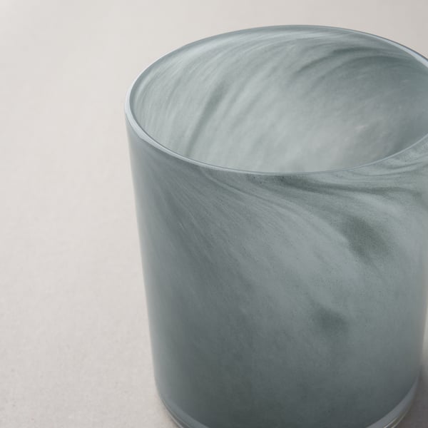 Kerzenhalter aus Milchglas, handgefertigt mit strukturierter Oberfläche, sitzt auf weißer Oberfläche.