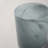 Kerzenhalter aus Milchglas, handgefertigt mit strukturierter Oberfläche, sitzt auf weißer Oberfläche.