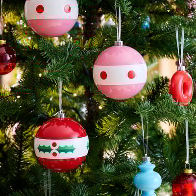 Roter und rosa Weihnachtsschmuck: einer mit Stechpalme, einer mit Punkten.