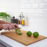 Person schneidet Limetten auf Holzbrett. Klinge scharf, Hand passt sich dem Griff an.