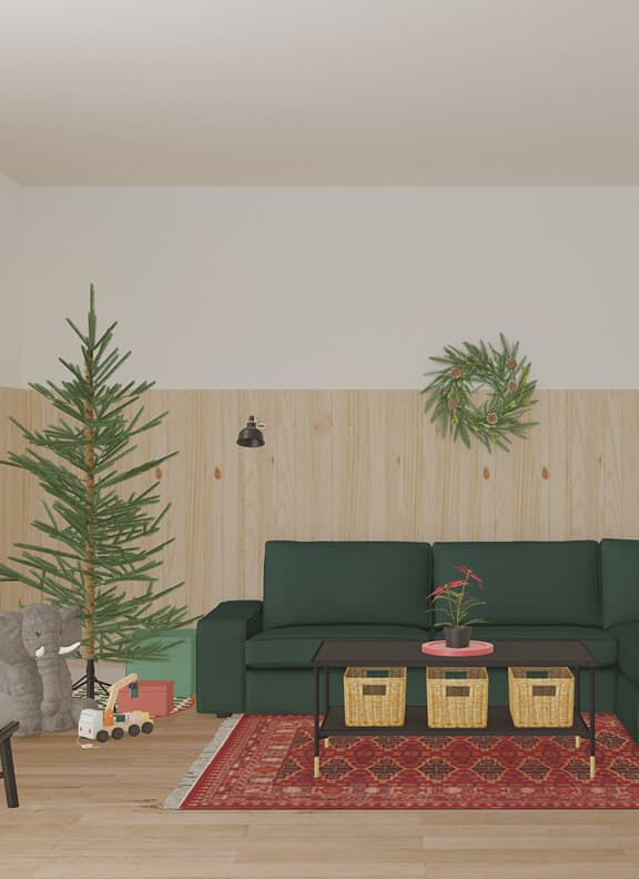 A festive virtual playroom created with IKEA Kreativ, showcasing a green sectional sofa, black coffee table, and red patterned rug. Light wood wall paneling adds a warm backdrop for a Christmas tree, holiday wreath, and colorful children’s toys.
