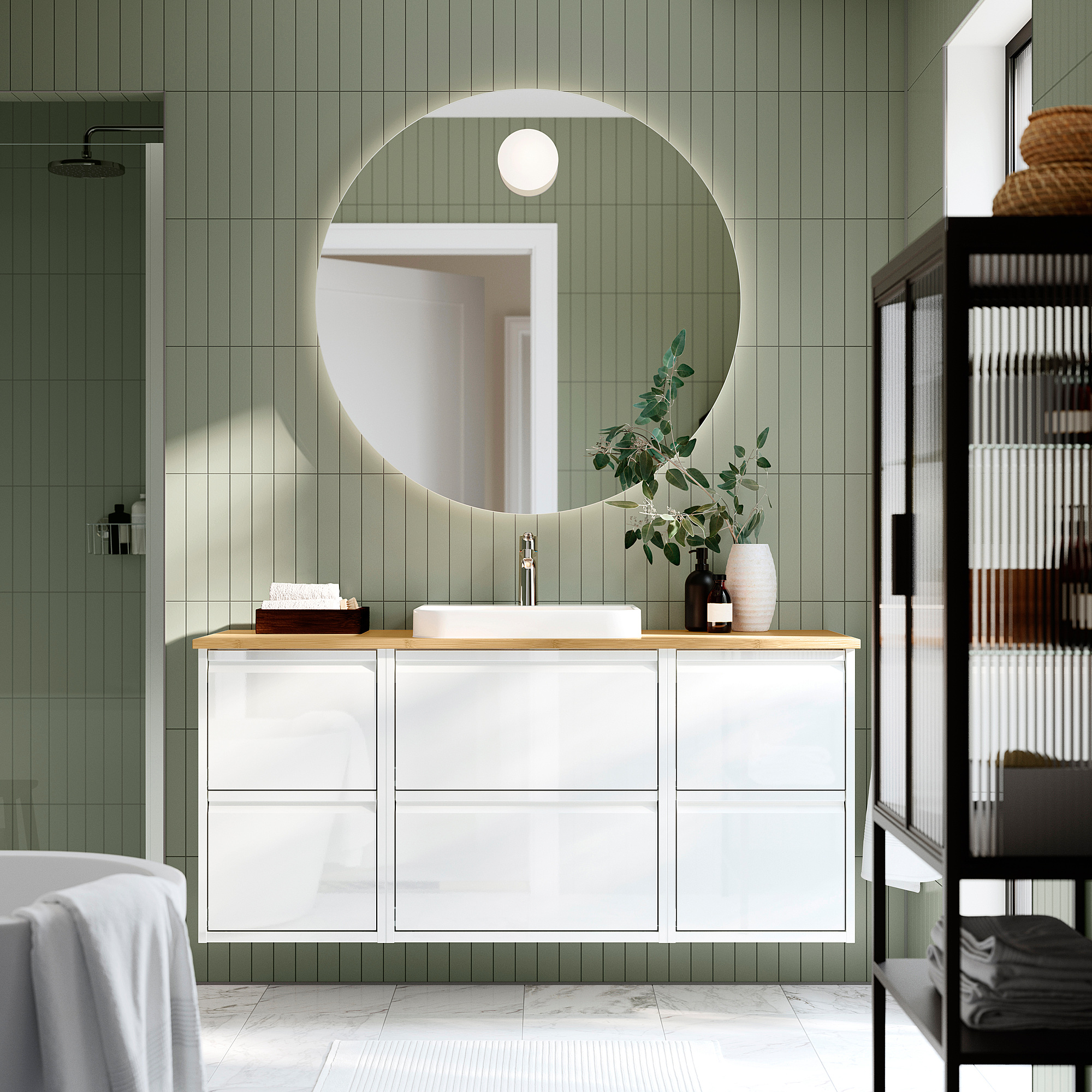Modern bathroom with white ÄNGSJÖN vanity, round mirror, green walls, marble floor, and black shelf. Sink and countertop are central and spacious.