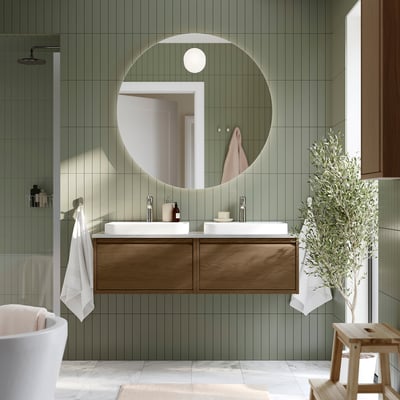 Modern bathroom with ÄNGSJÖN double vanity, two sinks, drawers, green tiles, round mirror, plant.