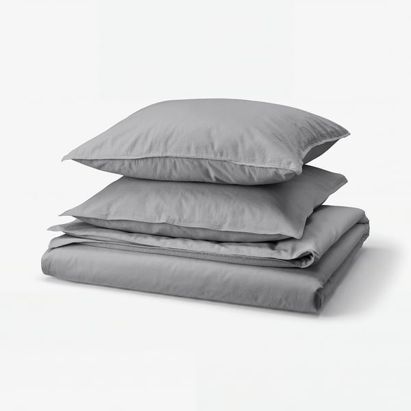 Grey cotton bedding set, including folded duvet and pillows, neatly stacked.