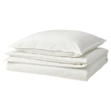 White bedding set. Three pillows and duvet stacked neatly. Soft, white cotton. Fresh and casual style.