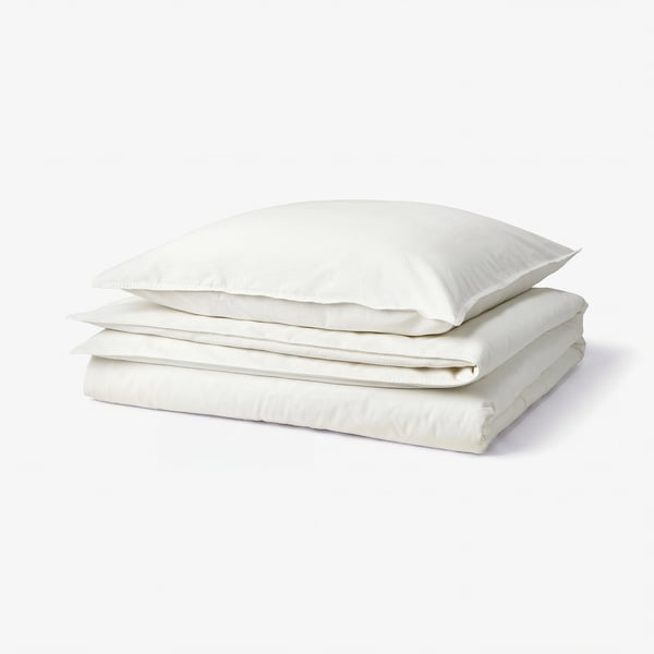 Clean white bedding stack on white background. Includes folded duvet and pillowcases in soft, washed cotton. Emphasises comfort and simplicity.