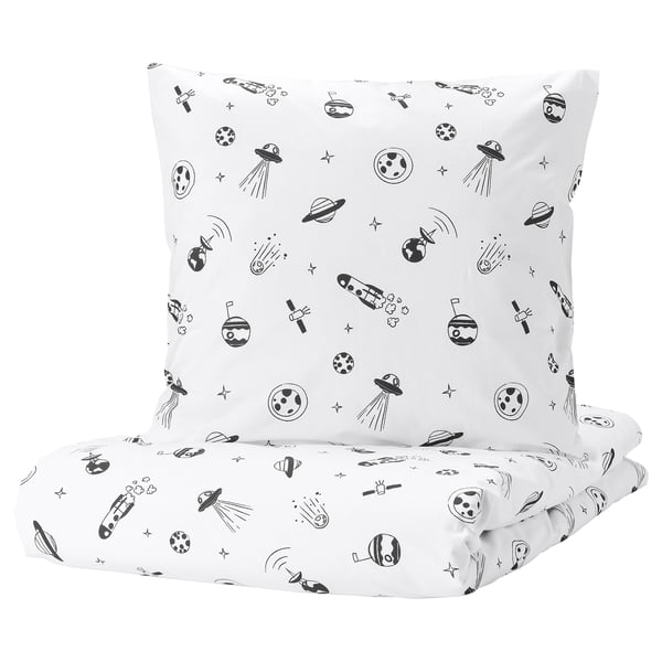 A white square pillow and folded sheet from the AFTONSPARV collection, featuring a black space theme with rockets, planets, and stars.