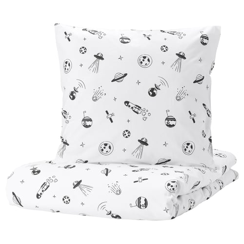 A white square pillow and folded sheet from the AFTONSPARV collection, featuring a black space theme with rockets, planets, and stars.
