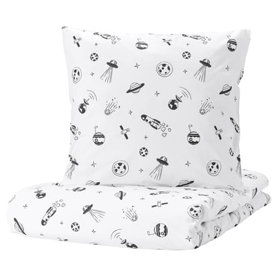 A white square pillow and folded sheet from the AFTONSPARV collection, featuring a black space theme with rockets, planets, and stars.