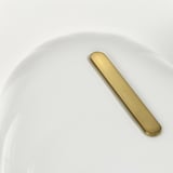 Gold handle on white plate; simple design.