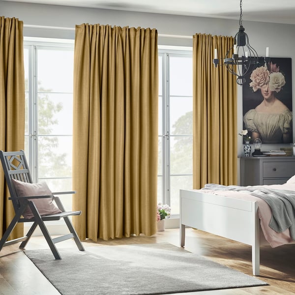 Mustard curtains block light, with bed, chair, and artwork.