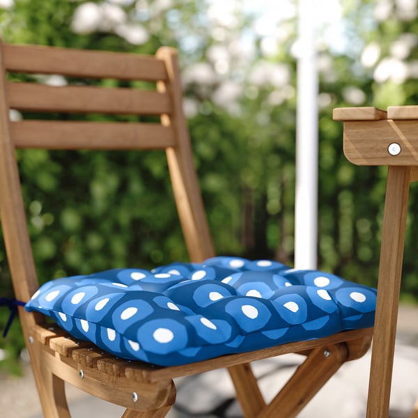 Blue outdoor chair with white circular pattern cushion on wooden chair.