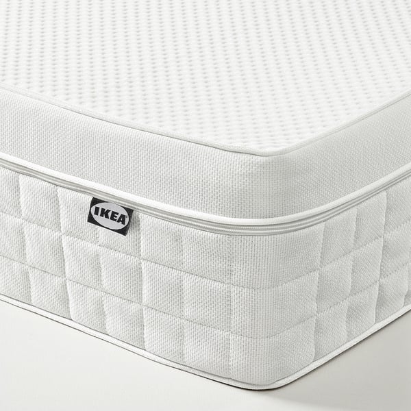 IKEA ÅVABERG mattress corner detail. Showing textured white surface, quilted side, and IKEA label.
