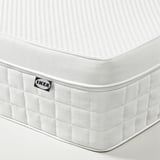 IKEA ÅVABERG mattress corner detail. Showing textured white surface, quilted side, and IKEA label.