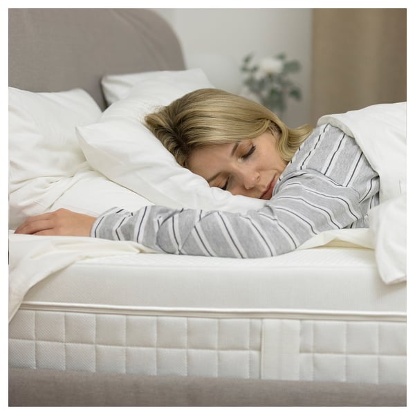 Woman sleeping peacefully on white ÅVABERG mattress.