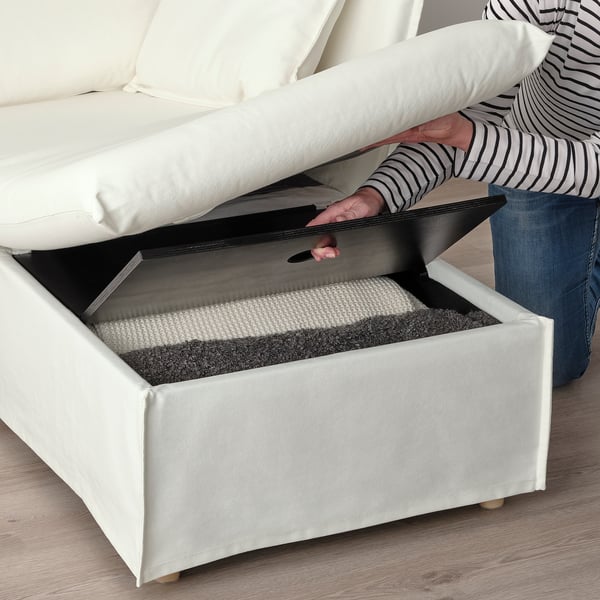Person lifting white sofa ottoman lid, revealing storage space lined with foam for comfort and organization, highlighting its practical design.