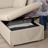 Person lifting sofa cushion to reveal foam-stored handle.