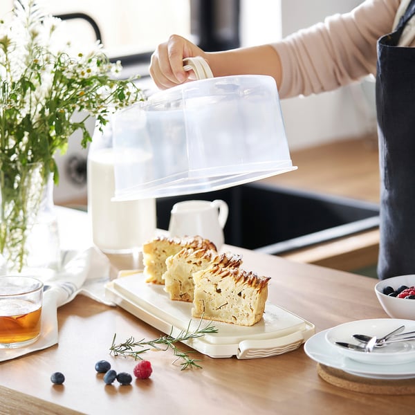 Person reveals cake slices on wooden table with plates and berries.