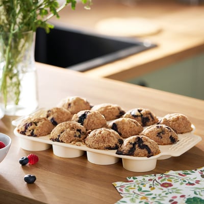 Tray of blueberry muffins on a wooden table next to napkins and fresh berries.