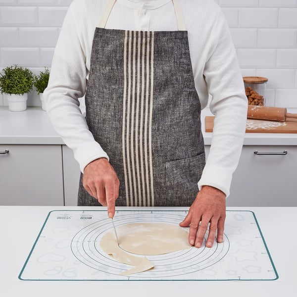 Person wearing an apron is using a baking mat with circular patterns, preparing dough on a countertop.