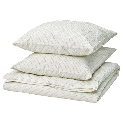 Three stacked white bed linens with green dot pattern, one folded, two pillows.