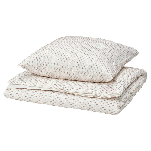 A stack of two pillows and a folded blanket, beige and white with a dotted pattern on a plain white background.