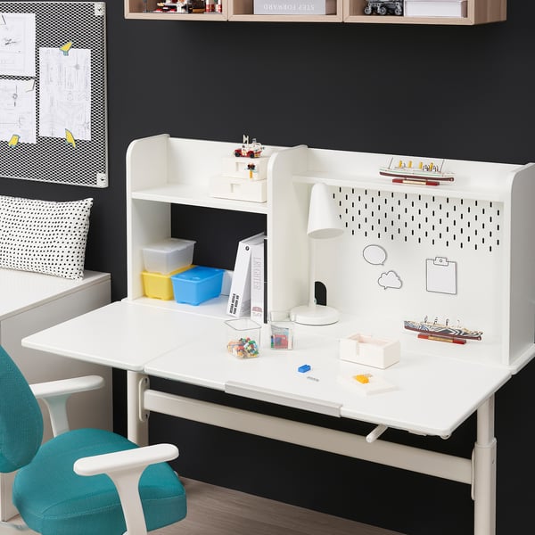 White kids adjustable desk with storage, pegboard, and lamp. Blue chair and colorful storage bins are visible.