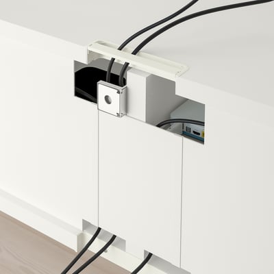Wall-mounted cable management system with white cover and cables visible.