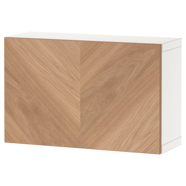 A white and light wood storage unit, part of the BESTÅ series, featuring a minimalist design with herringbone-patterned doors.