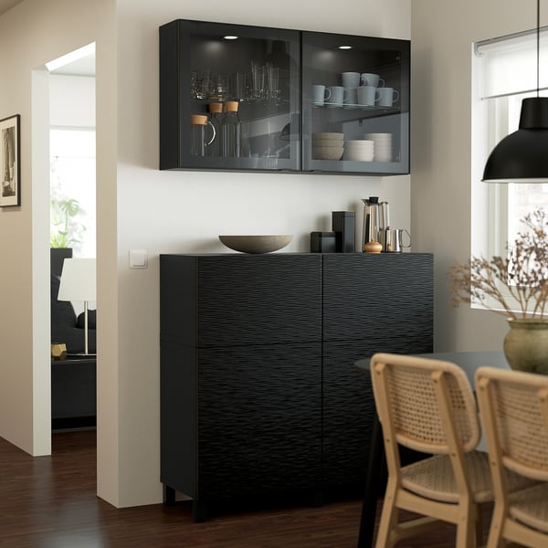 Modern kitchen with black BESTÅ cabinet, glass doors, and wicker chairs.