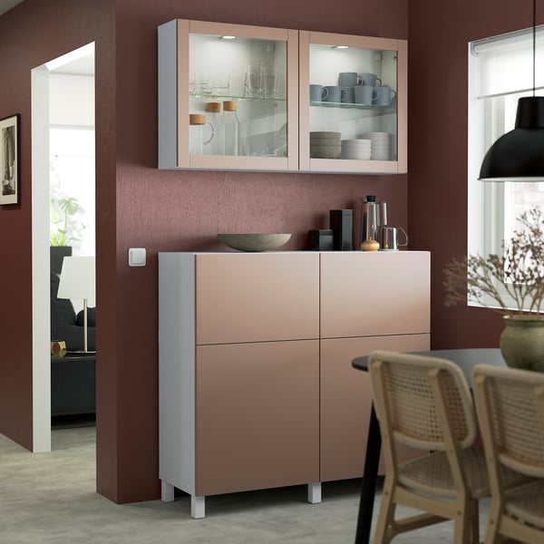 Modern kitchen with BESTÅ peach storage, glass display, and wicker chairs by window.