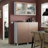 Modern kitchen with BESTÅ peach storage, glass display, and wicker chairs by window.
