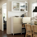 A modern kitchen with glass and wood cabinet displaying cups and bowls, providing both storage and decor.