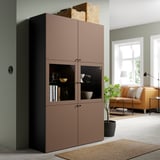 Brown BESTÅ cabinet with glass doors showing decor, beside green wall and yellow sofa, large with adjustable shelves.