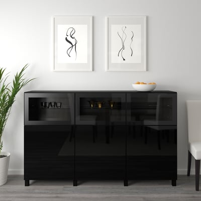 Black glass cabinet with adjustable shelves, displaying cups and bowls, framed art above.