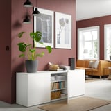 White BESTÅ sideboard stores books and decor; adjustable shelves. Hangs and pushes open.