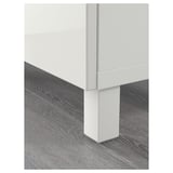 Modern white cabinet corner with sleek design resting on textured wooden floor.