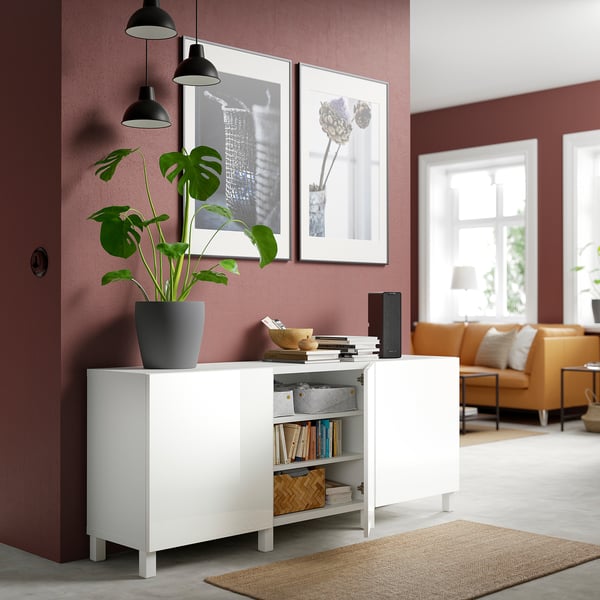 White BESTÅ sideboard displays books, plant, and bowl; offers storage and aesthetics in a red living room.