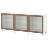 An IKEA BESTÅ sideboard in white and brown. It has three glass doors and adjustable shelves. The sleek design offers both storage and display.