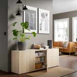 Modern living room with BESTÅ sideboard, adjustable shelves, books, decor, plant, and wall light.