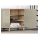 Open wooden storage unit inside light cabinet display, showing adjustable shelves with books.